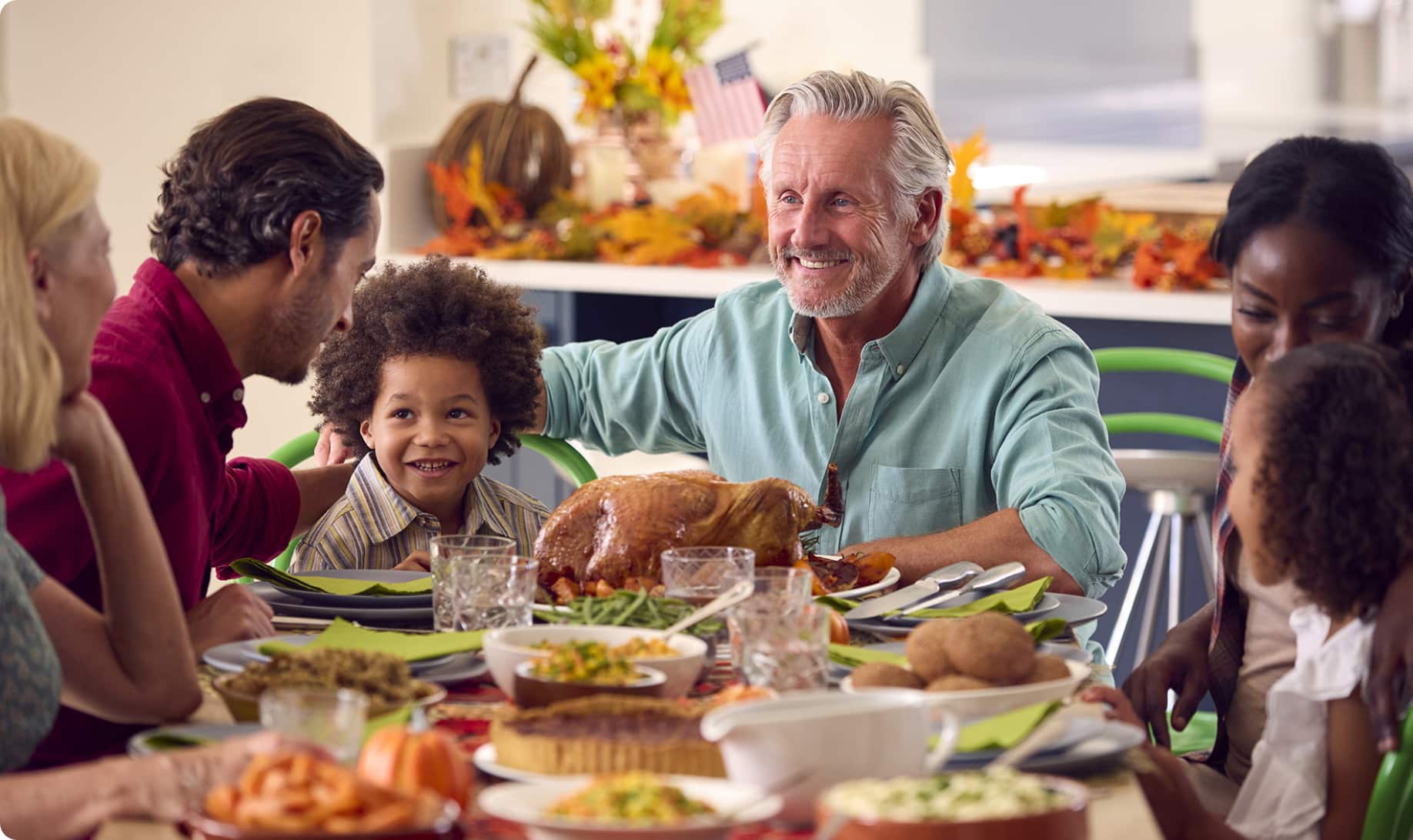 A middle-aged man and family sitting around a dinner table with an assortment of food