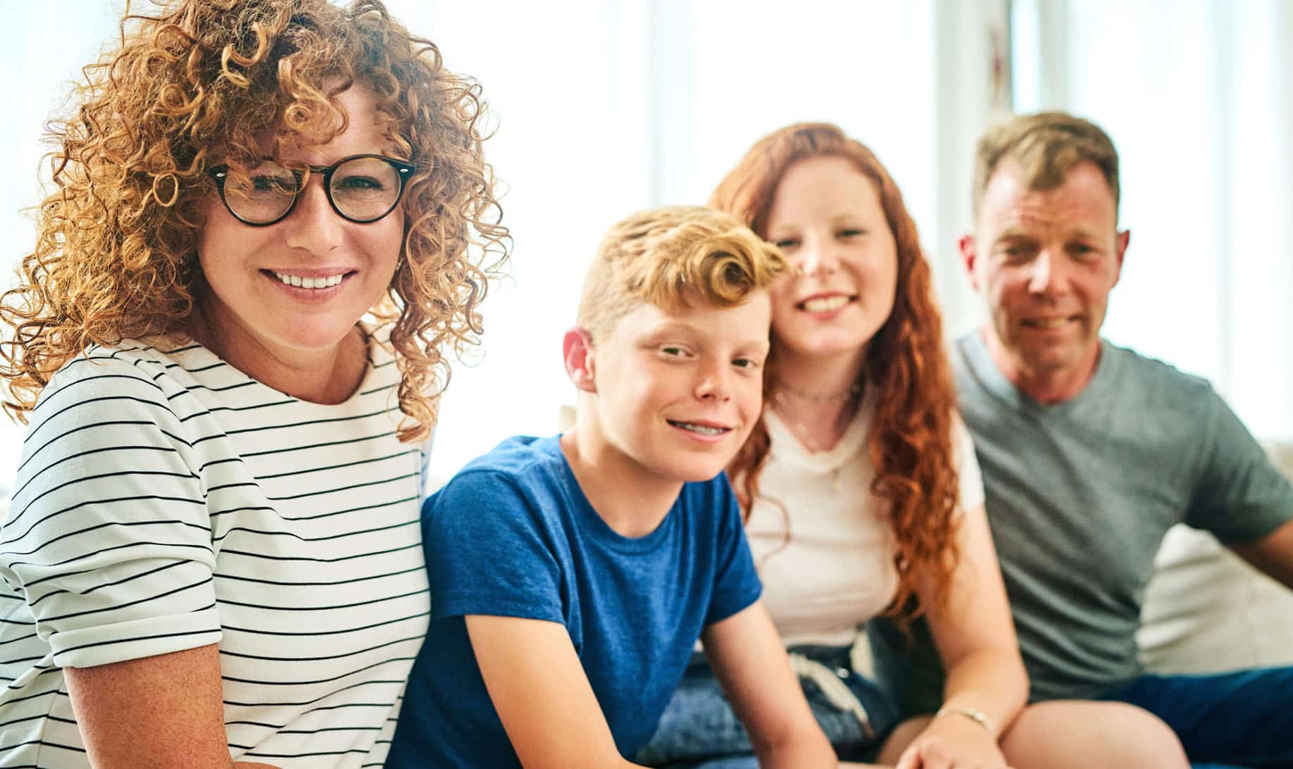 Family sat on a couch smiling at the camera