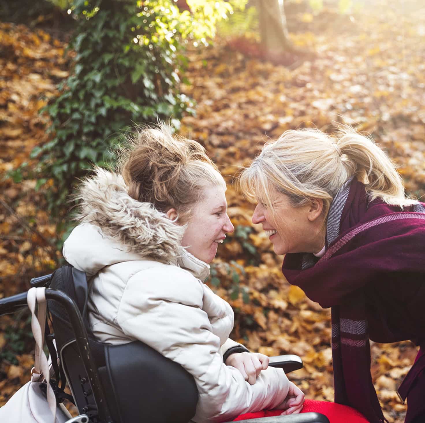 Older woman sharing a laugh with a younger woman in a wheelchair