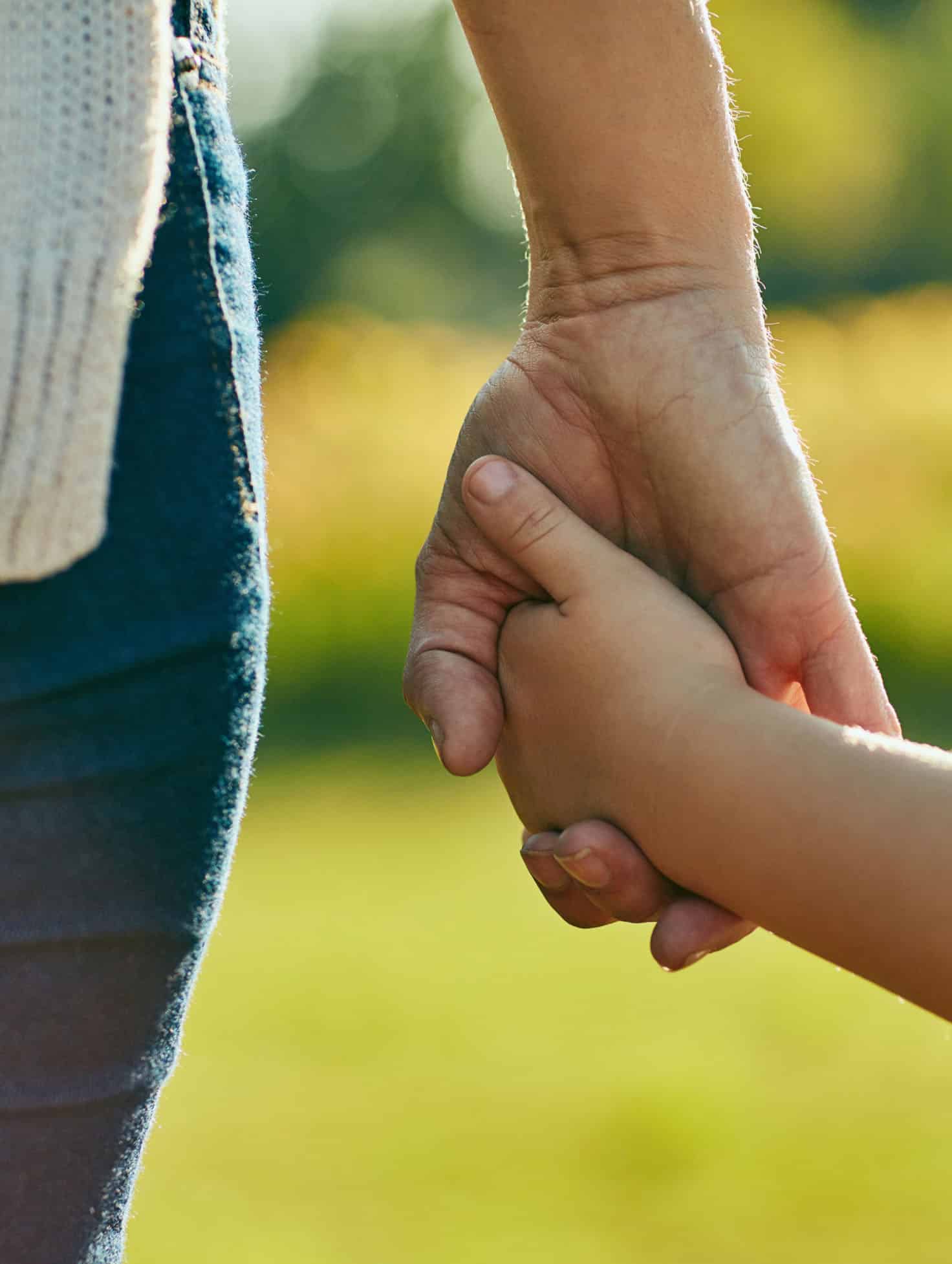 Close-up of an older person holding a young person's hand